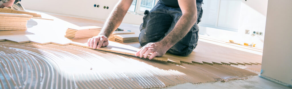 Bild von einem Mitarbeiter beim Fußbodenverlegen.